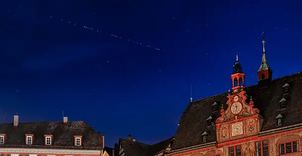 Starlink-Satelliten am Nachthimmel über dem Rathaus von Tübingen (Baden-Württemberg).